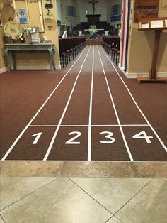 an indoor running track with numbers painted on the ground and chairs in the back area