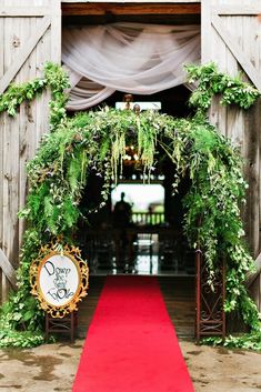 a red carpet is on the ground in front of a wooden structure with greenery