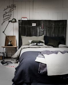 the bed is made up with black and white sheets, pillows, and blankets on it