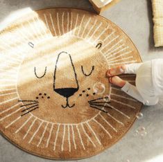 a child standing next to a rug with a lion face on it