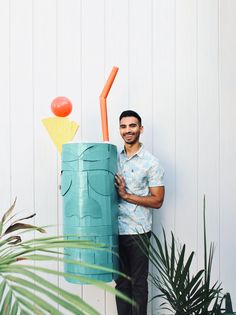 a man standing next to a tall blue container with an orange toothbrush sticking out of it