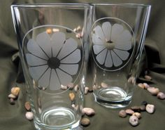 two glasses with flowers on them sitting next to each other