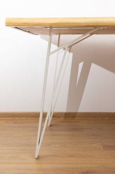 a wooden table sitting on top of a hard wood floor next to a white wall