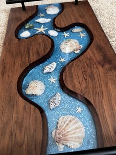 a wooden board with sea shells and stars on it in the shape of a river