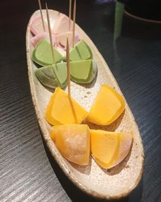 there are several pieces of fruit on a boat shaped plate with toothpicks in it