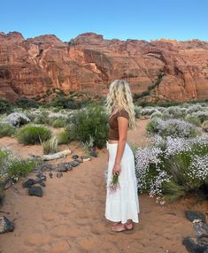 a woman is standing in the desert with her back to the camera and looking into the distance