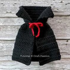 a crocheted black jacket with a red bow on the front and back side