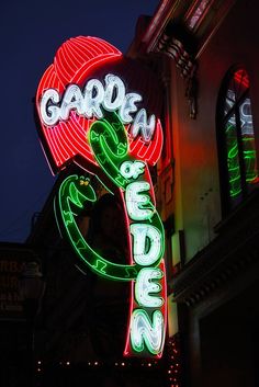 a neon sign that says garden greens on the side of a building at night time