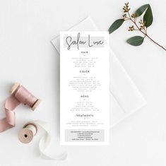 a pink and white wedding ceremony program on top of a table next to two spools of thread