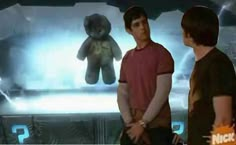 two people standing in front of a screen with a teddy bear on it