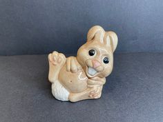 a ceramic animal figurine sitting on top of a gray surface with one paw in the air