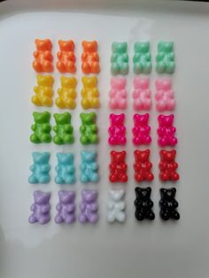 many different colors of gummy bears on a white surface with one black bear in the middle