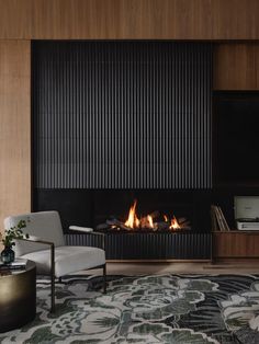 a modern living room with a fireplace and tv on the wall, along with two chairs