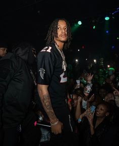 a man with dreadlocks standing in front of a crowd