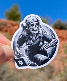 a person holding up a sticker with a skeleton on it's back and an image of a motorcycle rider in the background