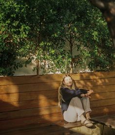 a woman sitting on top of a wooden bench