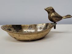 a gold bird figurine sitting on top of a metal bowl