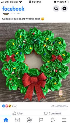 a green wreath decorated with red bows on top of a wooden table next to a cupcake