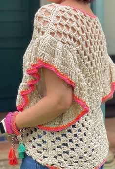 a woman wearing a crocheted top with tassels on the back and shoulder