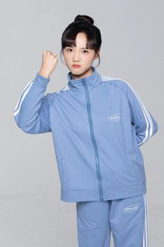 a woman in blue tracksuits posing for the camera with her fist raised up