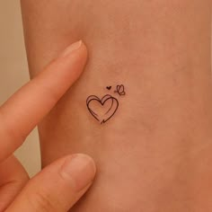 a small heart tattoo on the side of a woman's left arm and wrist