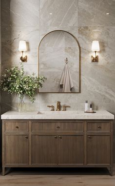 a bathroom vanity with marble counter top and two lights on the wall next to it