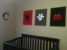 a baby's room with three paintings on the wall and a black crib