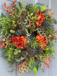 a wreath with orange and green flowers hanging on the front door to give it a festive feel