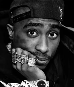 a black and white photo of a man with rings on his fingers