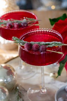 two glasses filled with raspberry martinis and garnished with fresh herbs