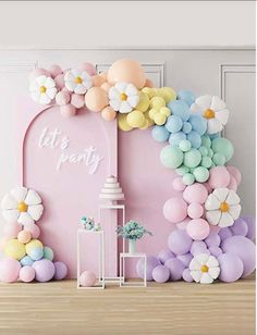 a pink backdrop with balloons and flowers on it for a baby's first birthday party