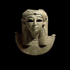 an ancient mask is shown against a black background in this image, there is a woman's face on top of the head