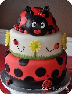 a three tiered cake decorated with ladybugs and daisies