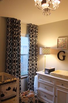 a baby's room with a crib, dresser and chandelier in it