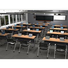 an empty classroom with many desks and laptops on the tables in front of them