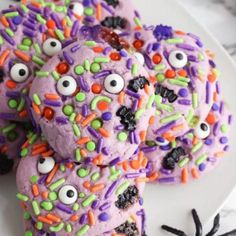 halloween cookies decorated with sprinkles and eyes on a white plate, ready to be eaten