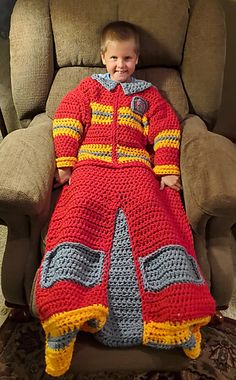 a little boy sitting in a big chair with a crocheted blanket on it