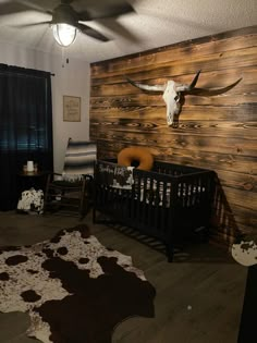 a baby's room with a cow skull mounted on the wall and other decor