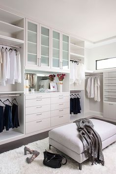 a white closet with lots of clothes and shoes on the floor in front of it