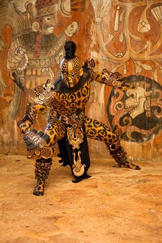 a woman is dancing in front of a wall with art work on the walls behind her