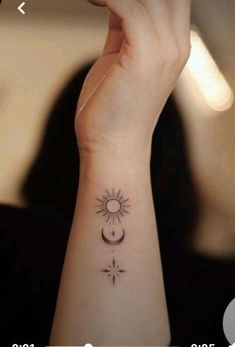 a woman's wrist with a small sun and moon tattoo on her left arm