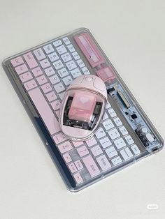 a pink computer mouse sitting on top of a keyboard with it's keys missing