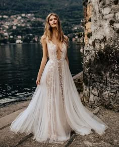 a woman in a wedding dress standing by the water