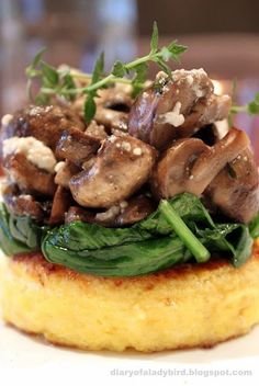 an omelet topped with mushrooms and spinach on top of a white plate