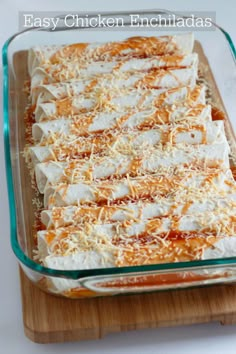 an easy chicken enchiladas recipe in a glass dish on a wooden cutting board