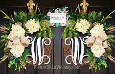 two monogrammed wreaths with white flowers and green leaves on the front door