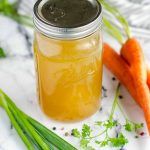 a jar filled with liquid next to some carrots