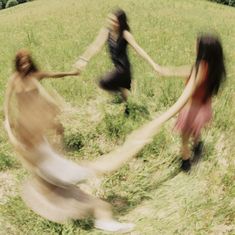 blurry photograph of three people holding hands in grassy field with trees in the background