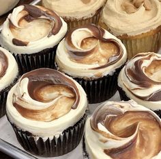 there are many cupcakes with chocolate frosting on them in the tray and ready to be eaten