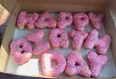 a box filled with pink frosted donuts and sprinkles on top